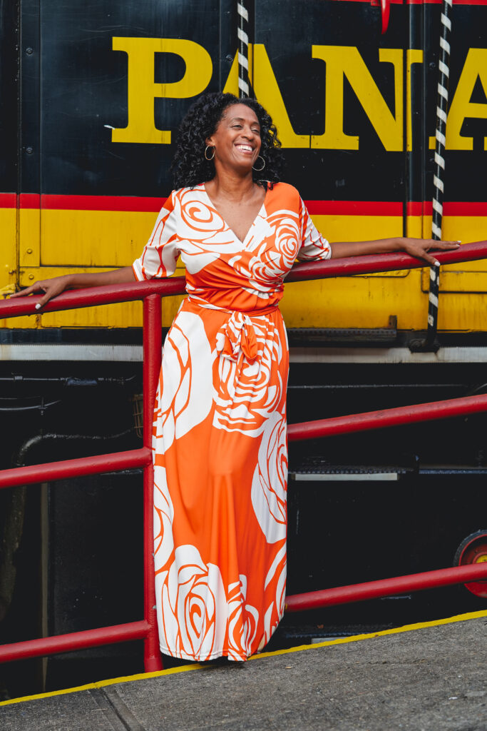 Photo of woman in orange dress standing in front of a train in Panama.